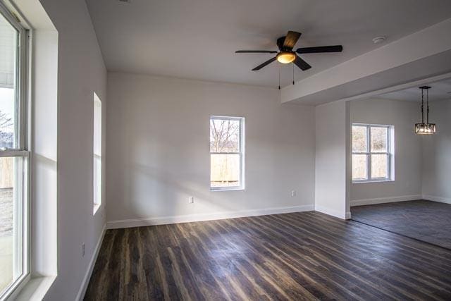 empty room featuring ceiling fan, dark hardwood / wood-style floors, and a healthy amount of sunlight