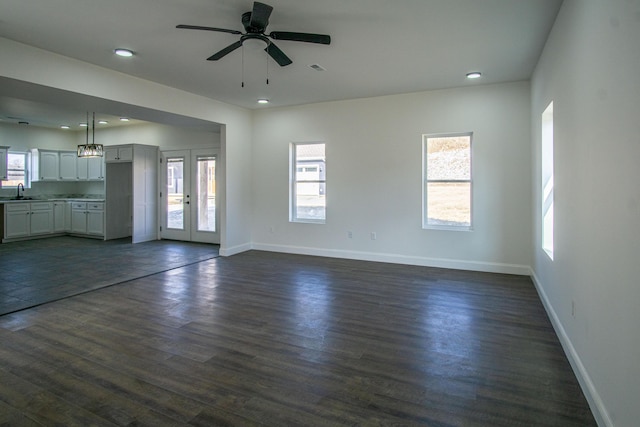 unfurnished living room featuring ceiling fan, sink, dark wood-type flooring, and french doors