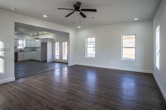 unfurnished living room featuring french doors, dark hardwood / wood-style flooring, ceiling fan, and a healthy amount of sunlight