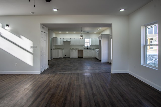 unfurnished living room with ceiling fan, sink, and dark hardwood / wood-style floors