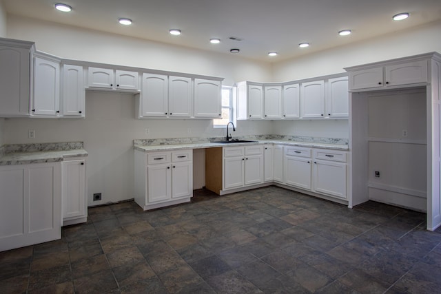 kitchen featuring white cabinets, light stone countertops, and sink