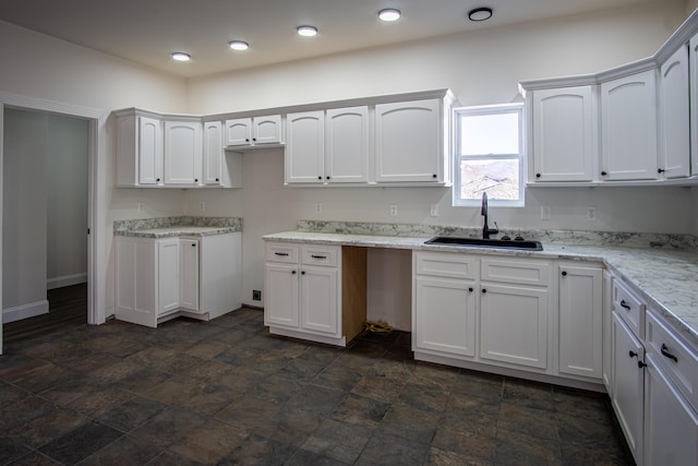 kitchen with white cabinets, light stone countertops, and sink