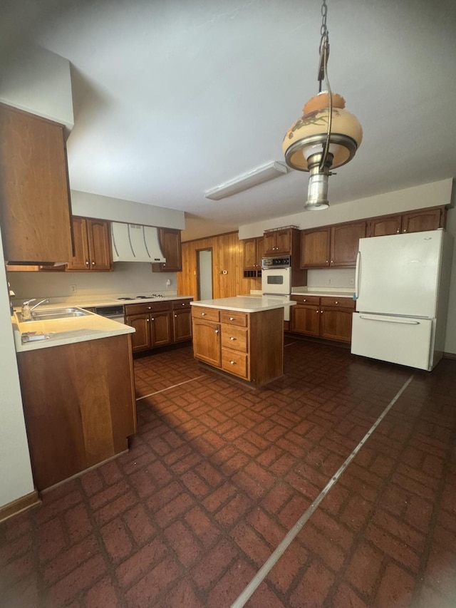 kitchen featuring a center island, white appliances, sink, decorative light fixtures, and extractor fan