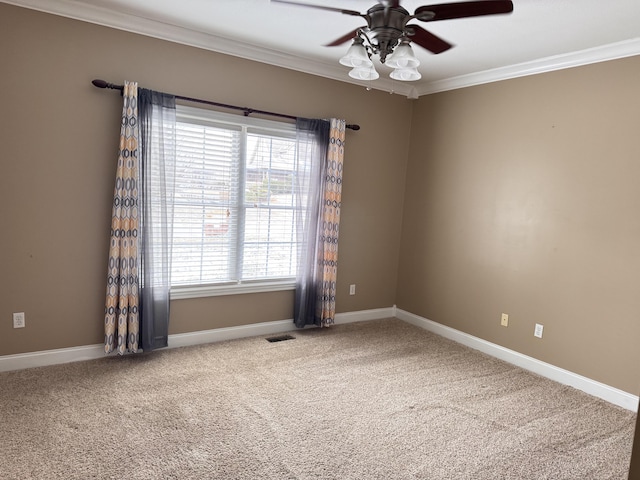 carpeted spare room with ceiling fan, plenty of natural light, and ornamental molding