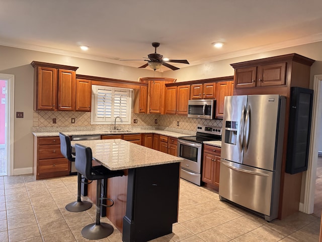 kitchen featuring appliances with stainless steel finishes, backsplash, a breakfast bar, ceiling fan, and a kitchen island