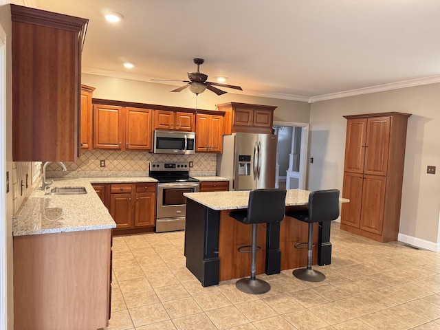 kitchen with sink, stainless steel appliances, tasteful backsplash, a kitchen bar, and a kitchen island