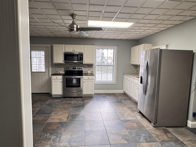 kitchen with decorative backsplash, white cabinetry, and appliances with stainless steel finishes