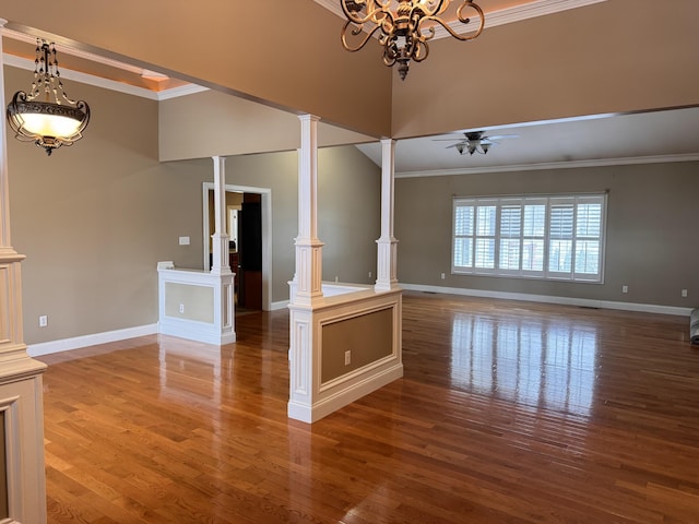 unfurnished living room with ceiling fan with notable chandelier, wood-type flooring, crown molding, and decorative columns