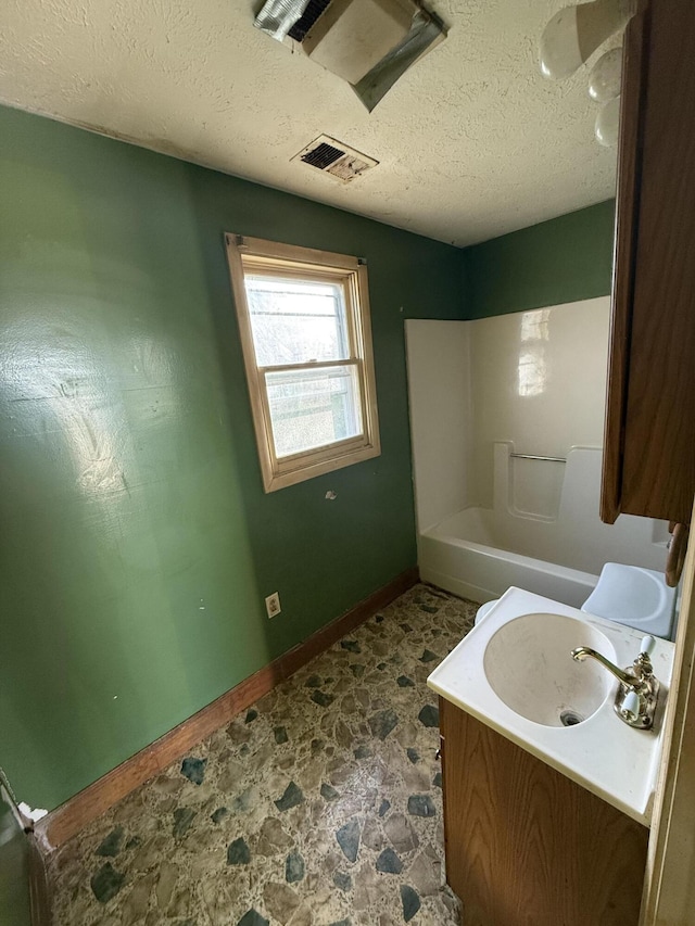 bathroom featuring shower / bathing tub combination, a textured ceiling, and vanity