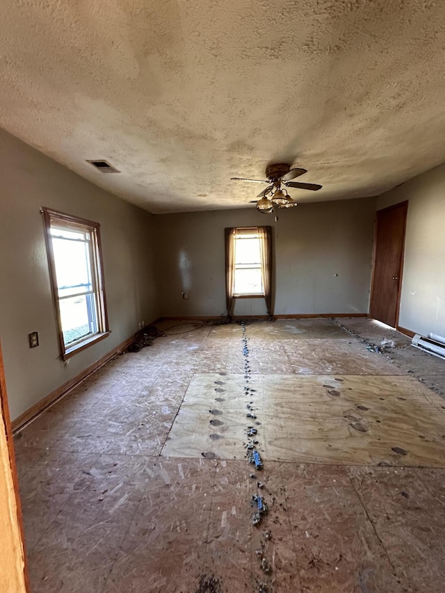 empty room featuring ceiling fan, a healthy amount of sunlight, and a textured ceiling