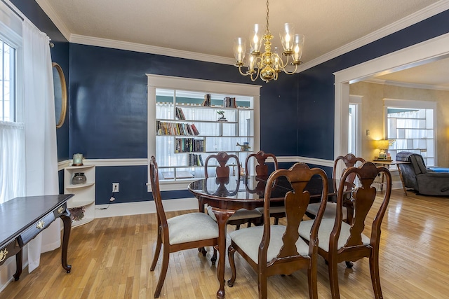 dining room featuring light wood-type flooring, a chandelier, and crown molding