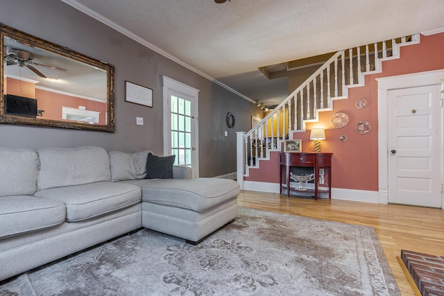 living room with ceiling fan, wood-type flooring, crown molding, and a textured ceiling