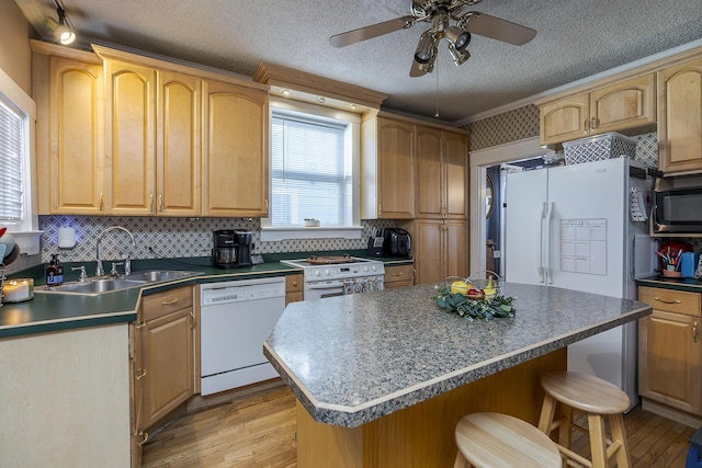 kitchen with ceiling fan, white appliances, a textured ceiling, a kitchen island, and sink