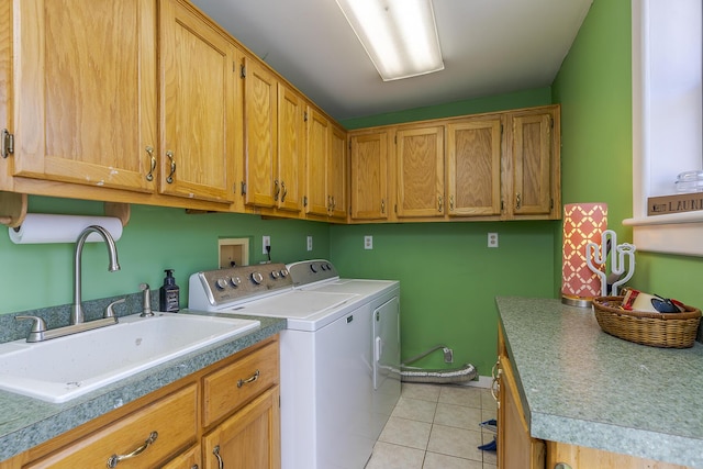 washroom with light tile patterned floors, sink, washer and dryer, and cabinets