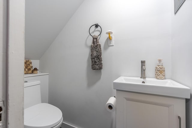 bathroom with toilet, vanity, and vaulted ceiling