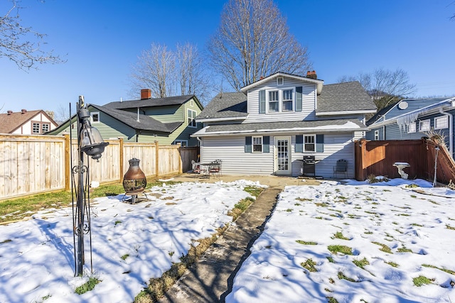 snow covered rear of property with an outdoor fire pit