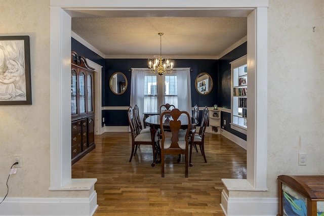 dining area featuring wood-type flooring, ornamental molding, a chandelier, and a textured ceiling