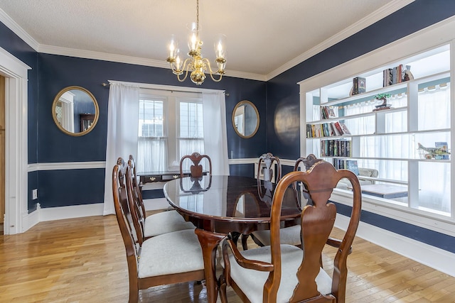 dining space featuring light wood-type flooring, crown molding, and a chandelier