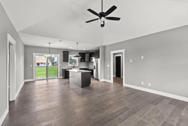 kitchen with dark hardwood / wood-style flooring, stainless steel fridge, pendant lighting, a kitchen island, and ceiling fan with notable chandelier