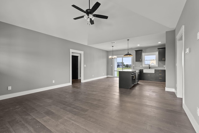 kitchen featuring a center island, ceiling fan with notable chandelier, sink, hanging light fixtures, and dark hardwood / wood-style flooring