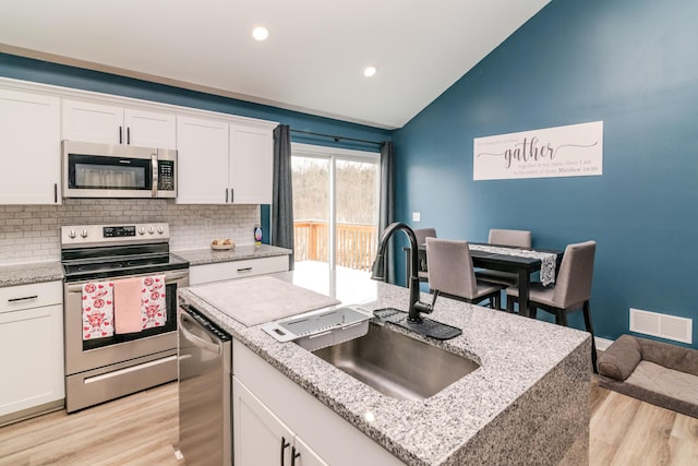 kitchen with sink, vaulted ceiling, white cabinetry, and appliances with stainless steel finishes