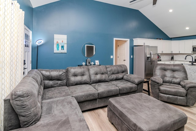 living room featuring sink, light hardwood / wood-style floors, high vaulted ceiling, and ceiling fan