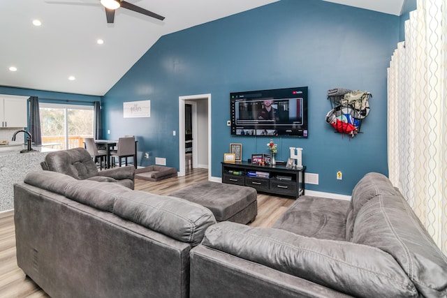 living room featuring ceiling fan, vaulted ceiling, and light wood-type flooring