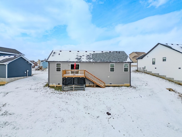 snow covered back of property with a deck