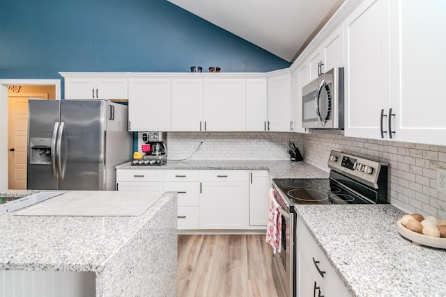 kitchen featuring white cabinets, decorative backsplash, vaulted ceiling, and stainless steel appliances