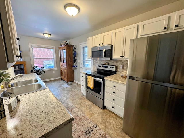 kitchen featuring sink, white cabinets, backsplash, light stone counters, and stainless steel appliances