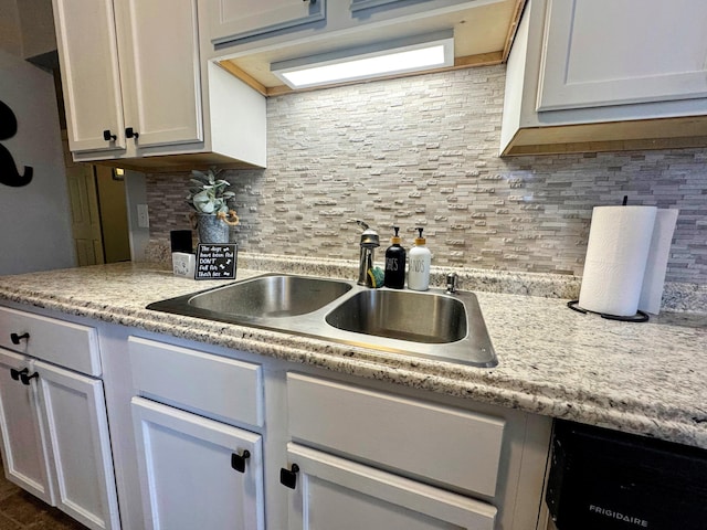 kitchen featuring tasteful backsplash, white cabinetry, dishwasher, and sink