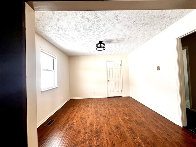 empty room with dark wood-type flooring and a textured ceiling