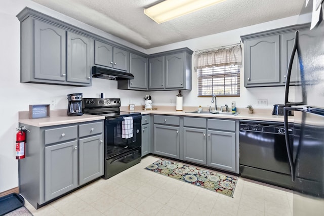 kitchen with black appliances, gray cabinetry, sink, and a textured ceiling