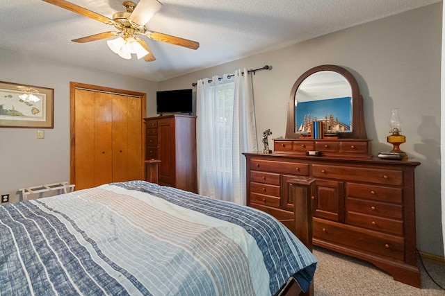 bedroom with ceiling fan, light colored carpet, a textured ceiling, and a closet