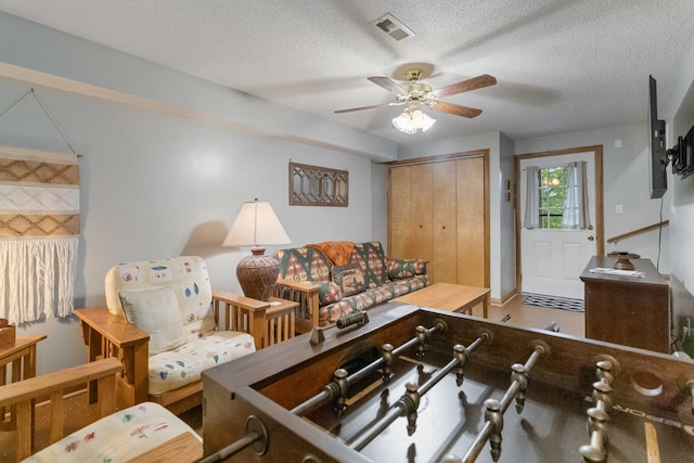 living room with a textured ceiling and ceiling fan