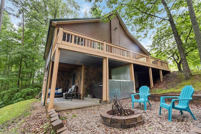 back of property featuring a deck, an outdoor fire pit, and a patio