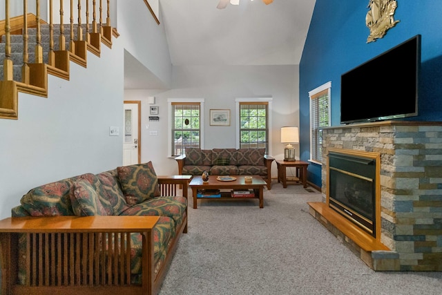 living room featuring a stone fireplace, ceiling fan, carpet, and high vaulted ceiling