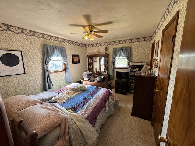 carpeted bedroom with ceiling fan and a textured ceiling