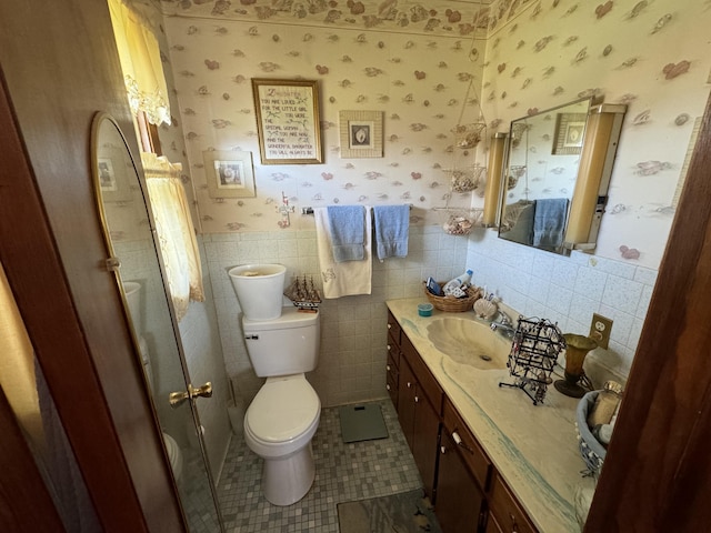 bathroom featuring tile patterned flooring, vanity, tile walls, and toilet