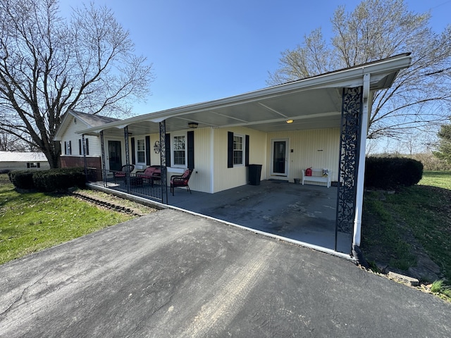 ranch-style house featuring a carport, covered porch, and a front lawn