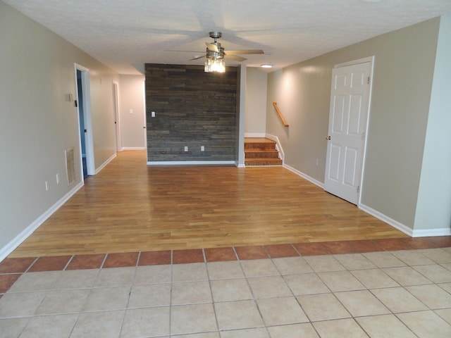 empty room featuring a textured ceiling, ceiling fan, and light tile patterned flooring