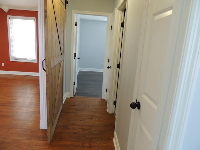 hall featuring dark hardwood / wood-style floors, a barn door, and ornamental molding