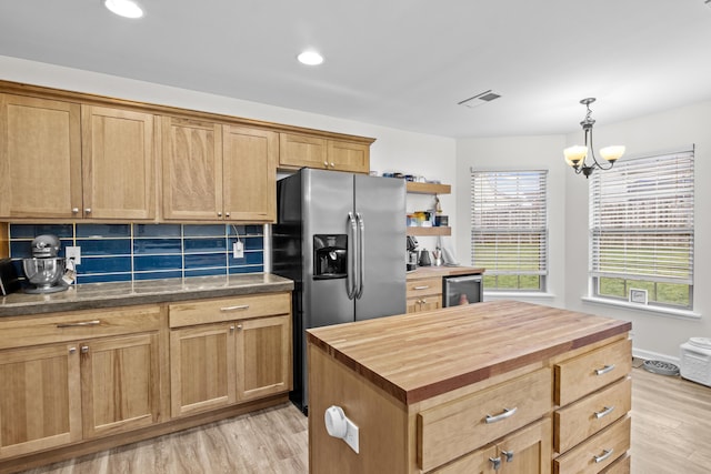 kitchen with butcher block countertops, stainless steel fridge, decorative backsplash, and a kitchen island