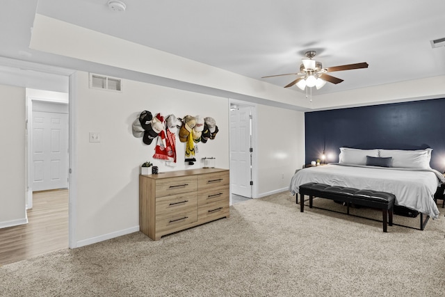 bedroom with a raised ceiling, ceiling fan, and light colored carpet