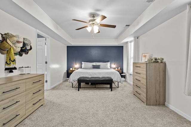 bedroom featuring a tray ceiling, ceiling fan, and light carpet