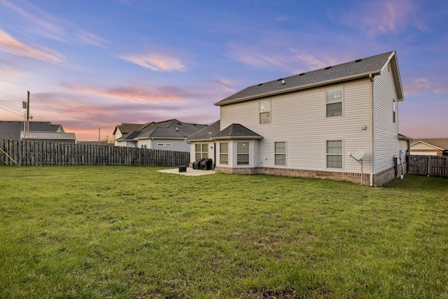 back house at dusk featuring a patio area and a yard