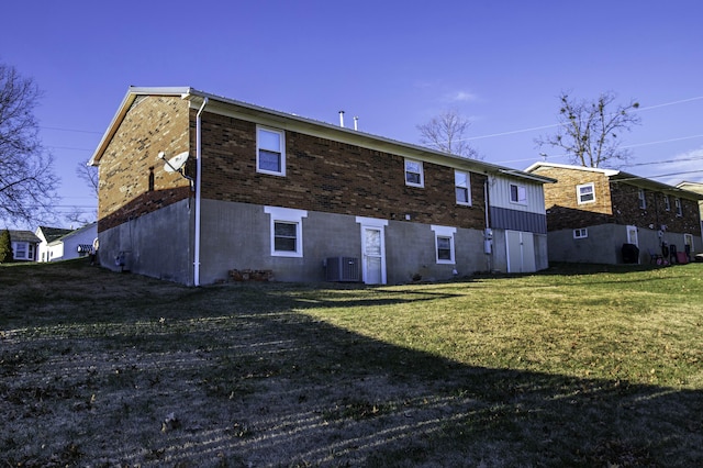 rear view of property with a lawn and cooling unit