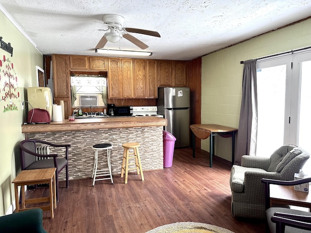 kitchen featuring dark wood-type flooring, a textured ceiling, stainless steel refrigerator, kitchen peninsula, and ceiling fan