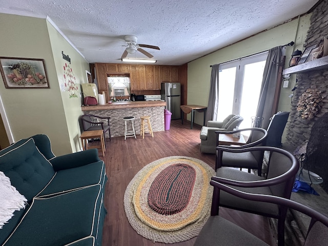 living room featuring ceiling fan, dark wood-type flooring, and a textured ceiling