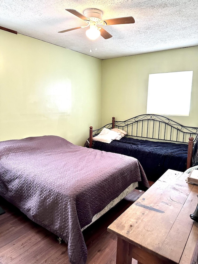 bedroom featuring ceiling fan, dark hardwood / wood-style floors, and a textured ceiling